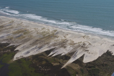 overwash moves sand, typically from ocean-side to bay-side, so barrier islands migrate rather than drown as sea level rises