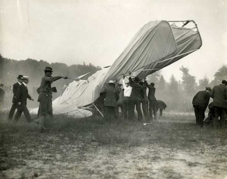 rescuers seek to extract Orville Wright from the wreckage, while others care for Lt. Thomas Selfridge (on right)