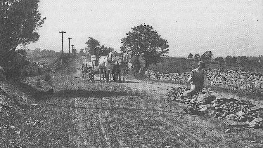 worker using a round headed hammer to break limestone into the proper sized road metal in order to maintain a section of the Valley Pike