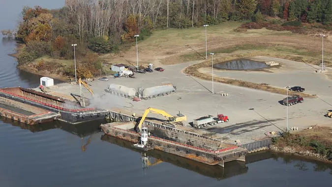 relatively dry dredge spoils were dug out of barges, placed in trucks, and then transported to the sand and gravel pit